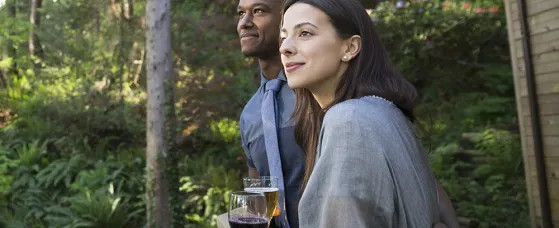 Couple drinking on cabin balcony in woods