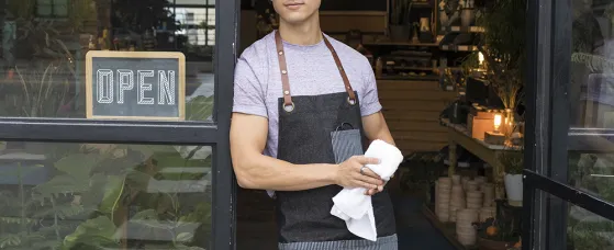 Pensive male shop owner standing in doorway looking away in anticipation