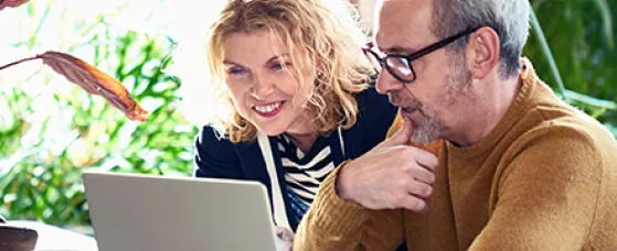 Mature couple in their 50s using computer at home.