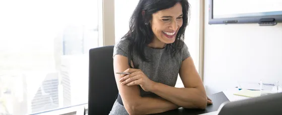 Smiling woman video conferencing at laptop in conference room
