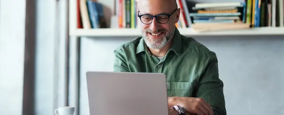  Smiling Man Working on Laptop in Modern Workspace with Bookshelves