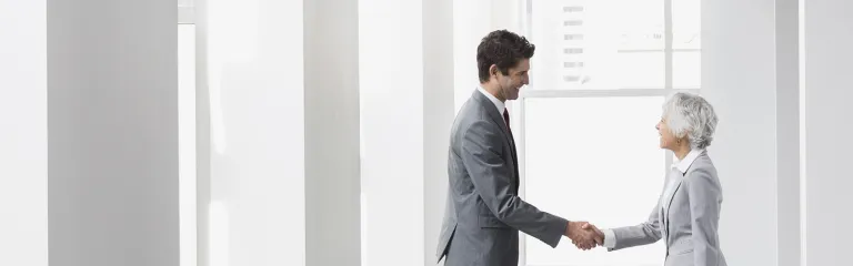 Businessman and businesswoman handshaking in empty office