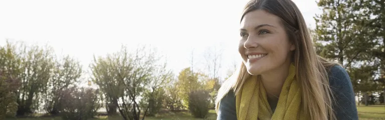 Smiling woman with bicycle looking away in sunny park