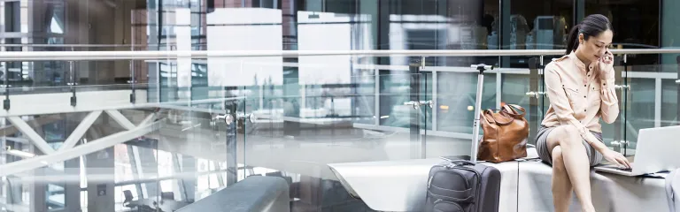Businesswoman using laptop and cell phone in airport