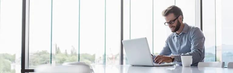 Man using laptop sitting at conference table in office