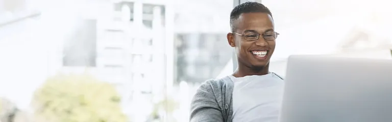 Shot of a handsome young man using his laptop while sitting on a sofa at home