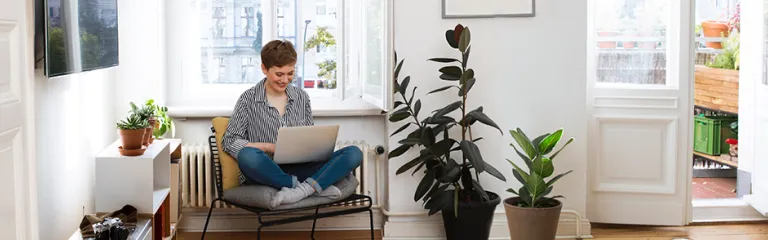 Woman sitting in chair at home, using laptop