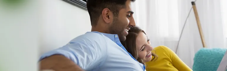 Young couple relaxing using digital tablet on living room sofa