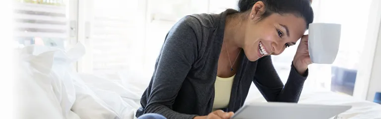 Smiling woman using digital tablet on bed