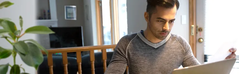 A man with credit card paying bills at laptop