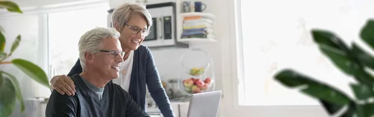 Senior couple using laptop at kitchen table