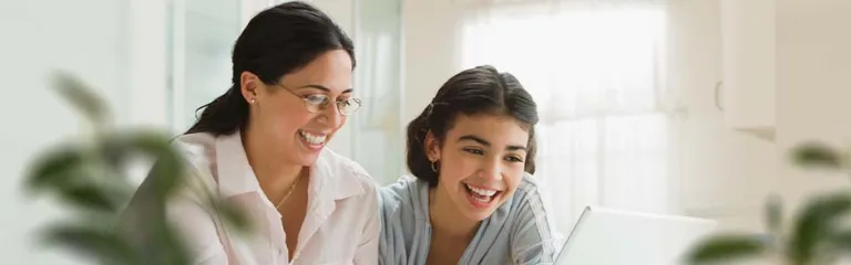 Mom and teen daughter using laptop