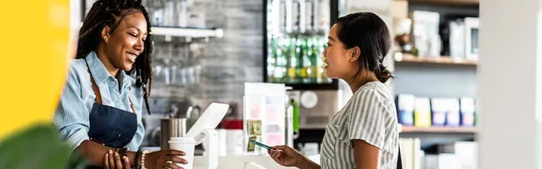 Young woman paying for coffee with debit card